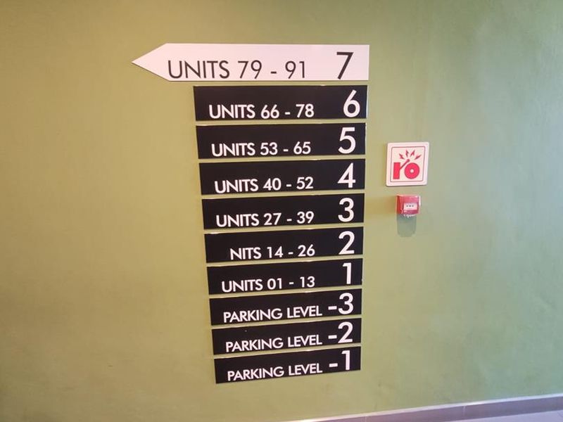 A clear directional signage board located in the apartment building lobby, indicating unit numbers and parking levels.