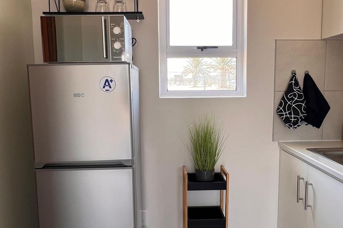 A clean and functional kitchen area featuring white cabinetry, tiled flooring, and a window providing natural light.