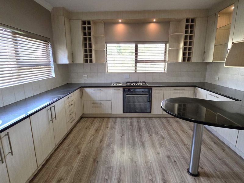 Modern kitchen featuring light wood cabinetry, dark granite countertops, integrated gas hob and oven, and a convenient breakfast bar.