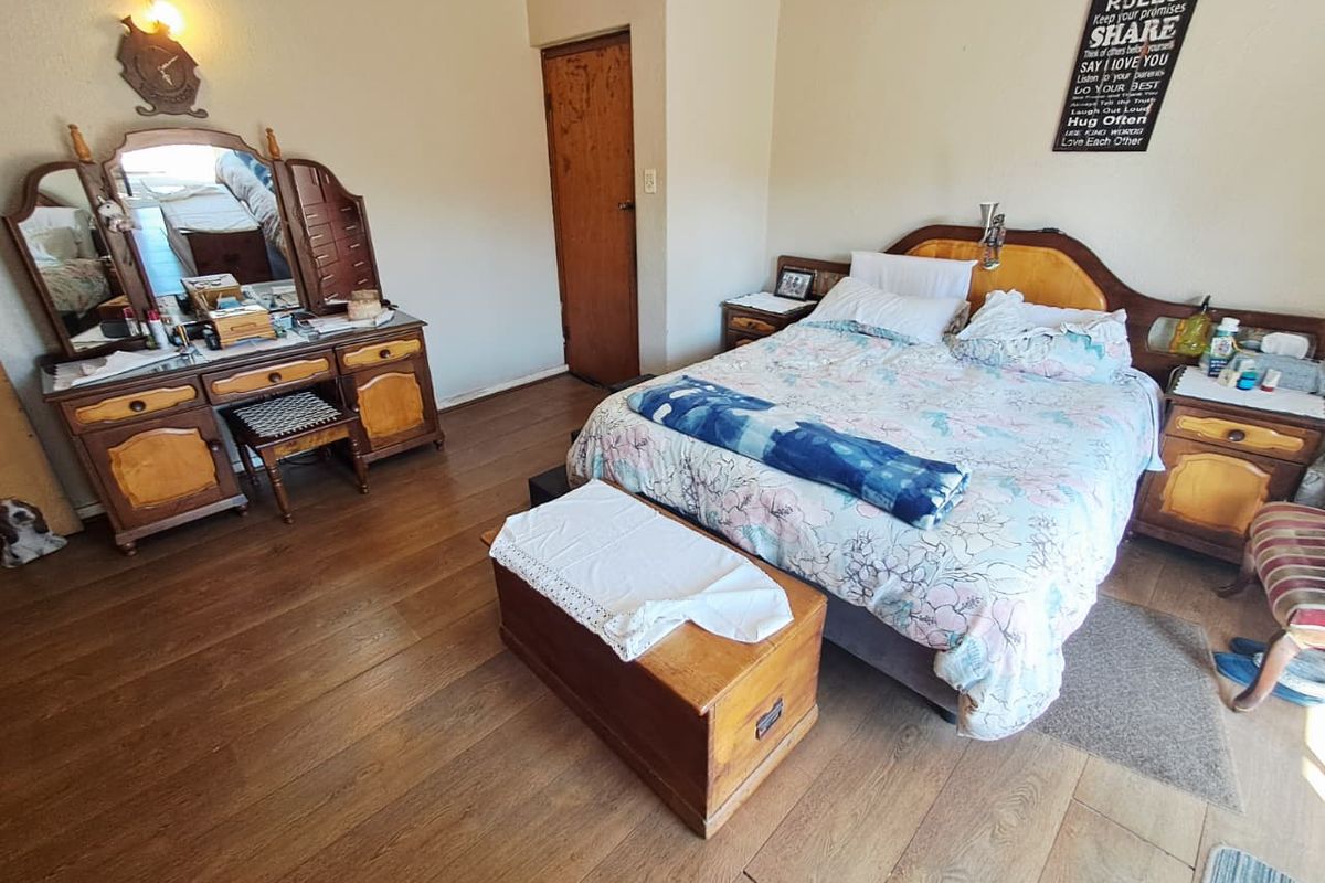 A spacious bedroom featuring laminate flooring and a neutral wall finish, providing a functional and comfortable sleeping area.