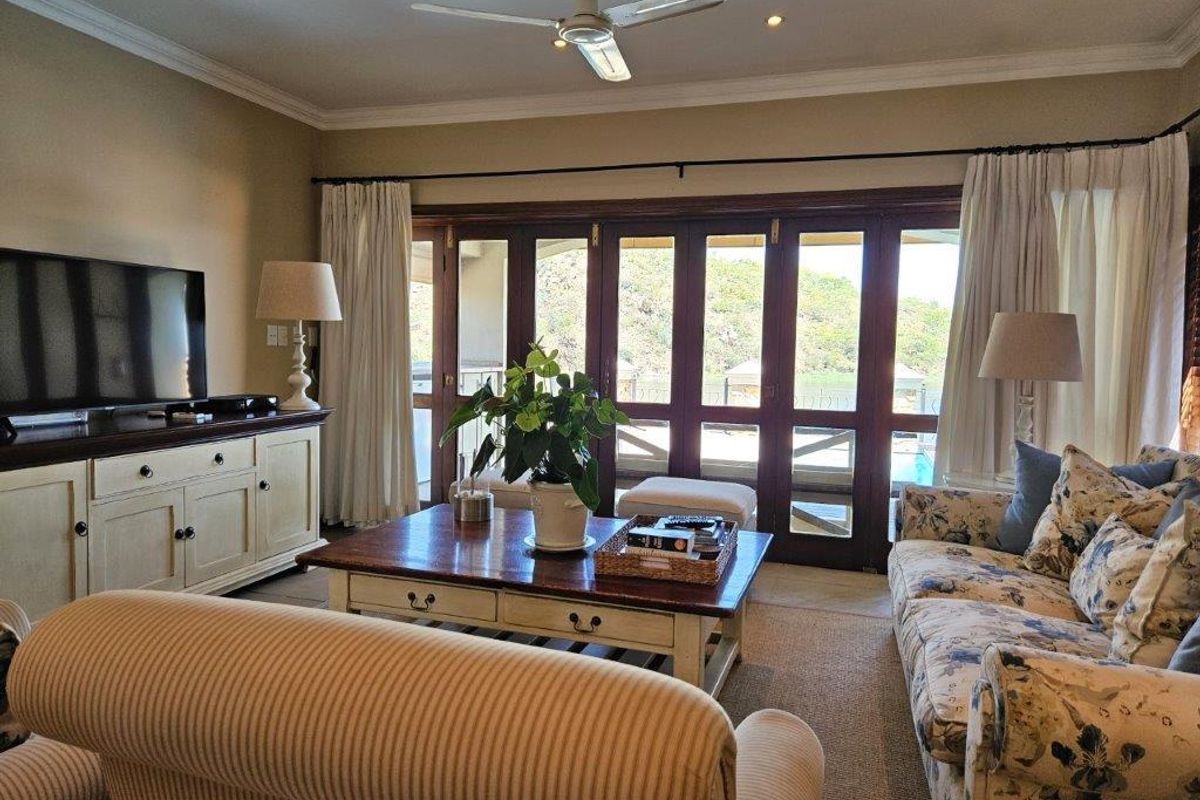 A comfortable living room featuring large wooden folding doors that open to an outdoor area, complemented by recessed ceiling lighting and a central ceiling fan.