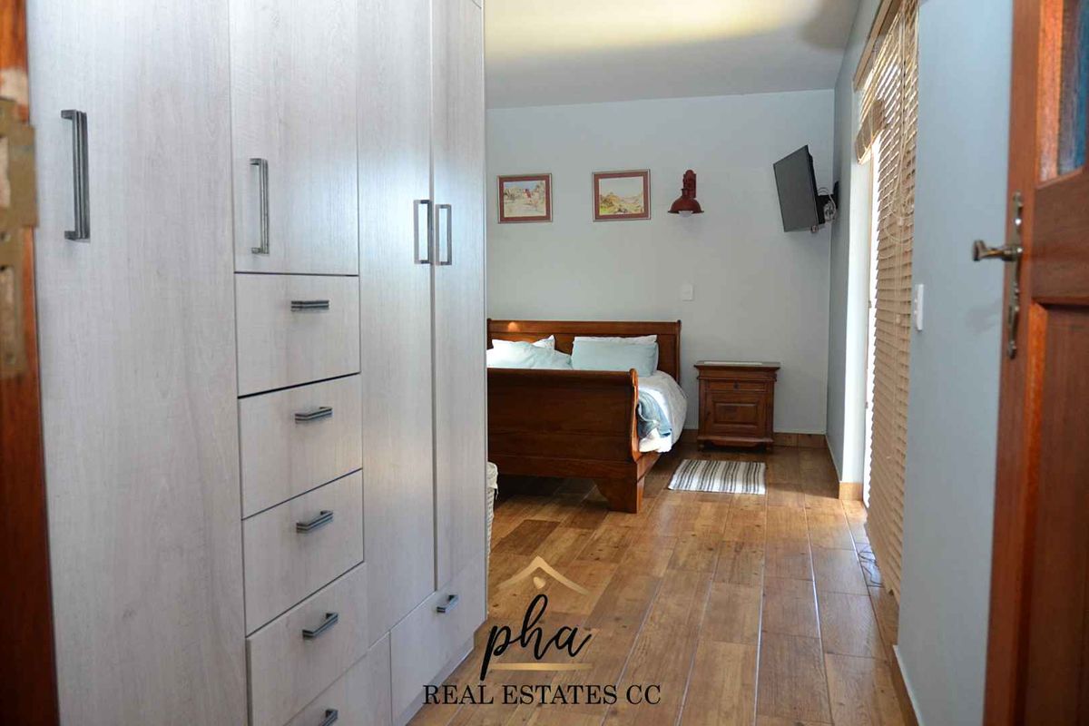 A bedroom featuring built-in light wood cabinetry, wood-look tile flooring, and direct access to an outdoor area through a glass door.