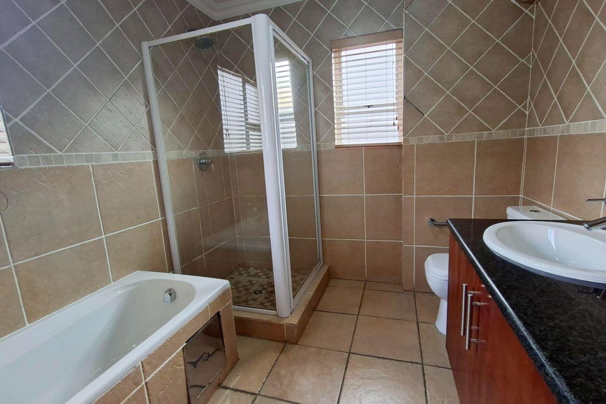 A functional bathroom featuring a built-in bathtub, separate shower enclosure, vanity cabinet with granite countertop, and neutral tiled finishes.