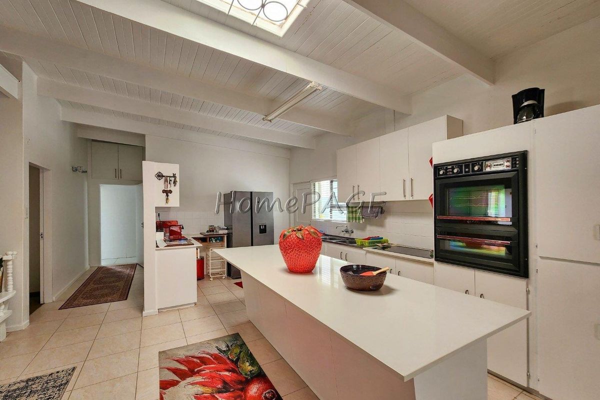 Spacious kitchen featuring a large central island, built-in double oven, ample cabinetry, and a skylight providing natural light.