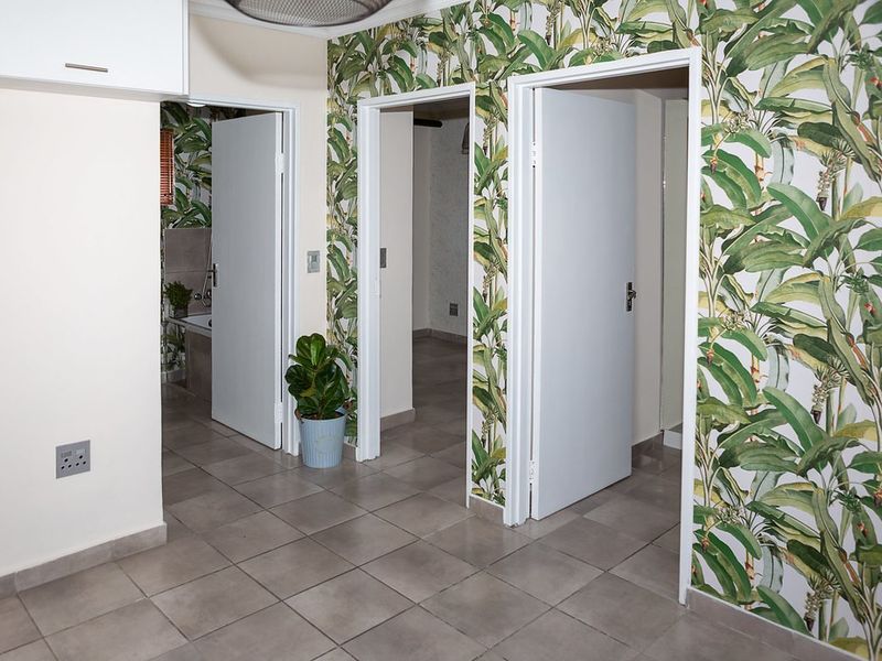 A tiled hallway featuring decorative botanical wallpaper and multiple internal doorways leading to adjacent rooms.