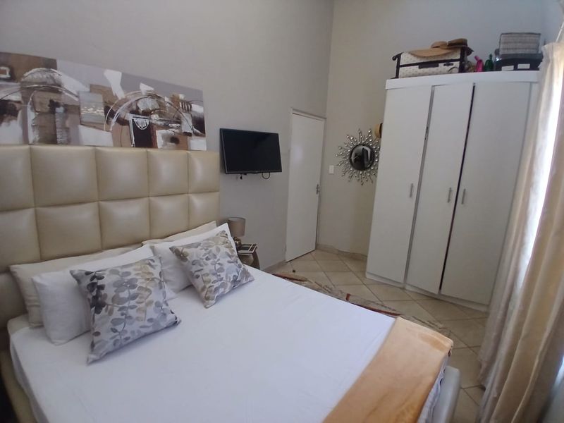 A bedroom featuring tiled flooring and a built-in wardrobe, offering a functional and neutral living space.