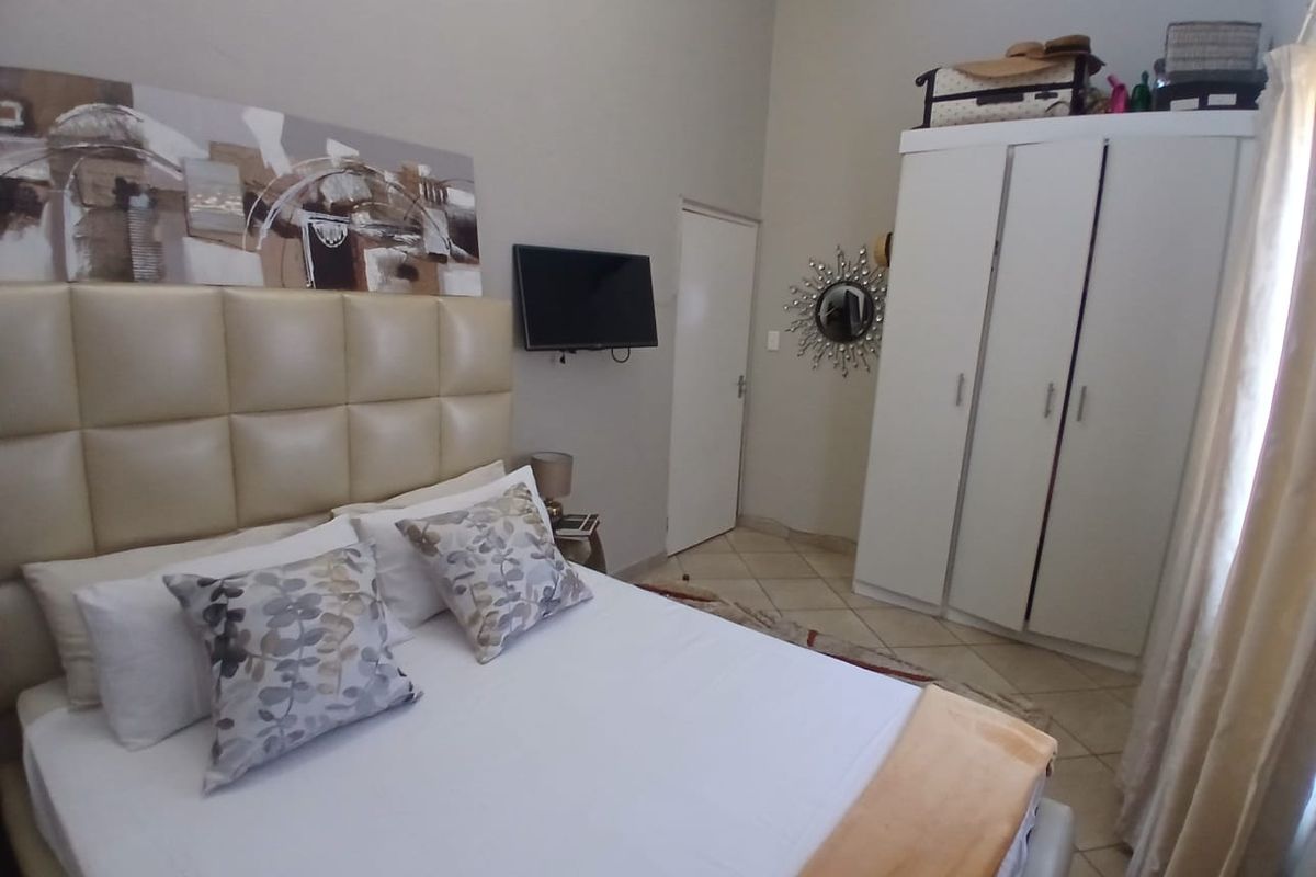 A bedroom featuring tiled flooring and a built-in wardrobe, offering a functional and neutral living space.