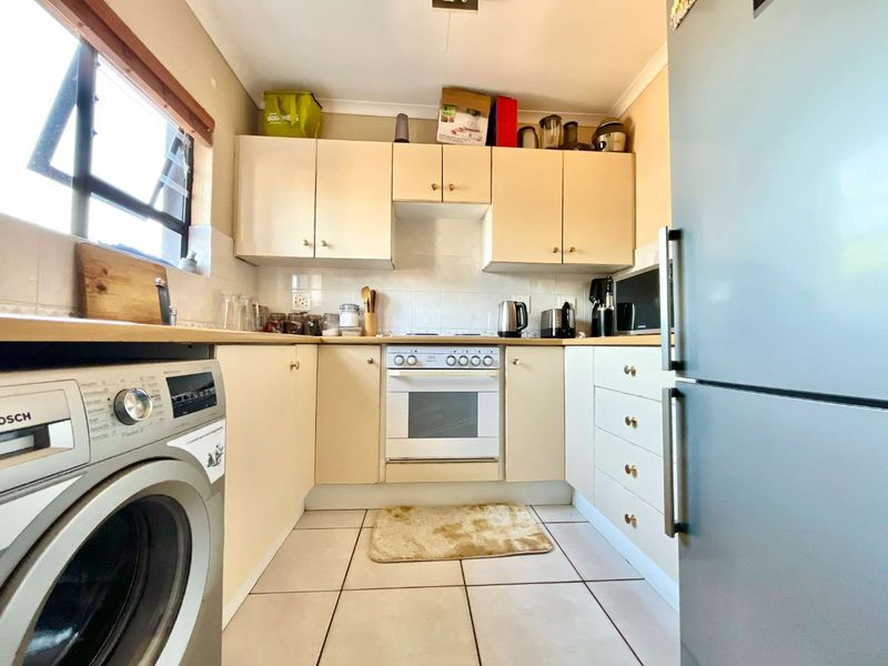 A compact kitchen featuring built-in cabinetry, tiled flooring, a built-in oven, and a hob with a tiled backsplash.