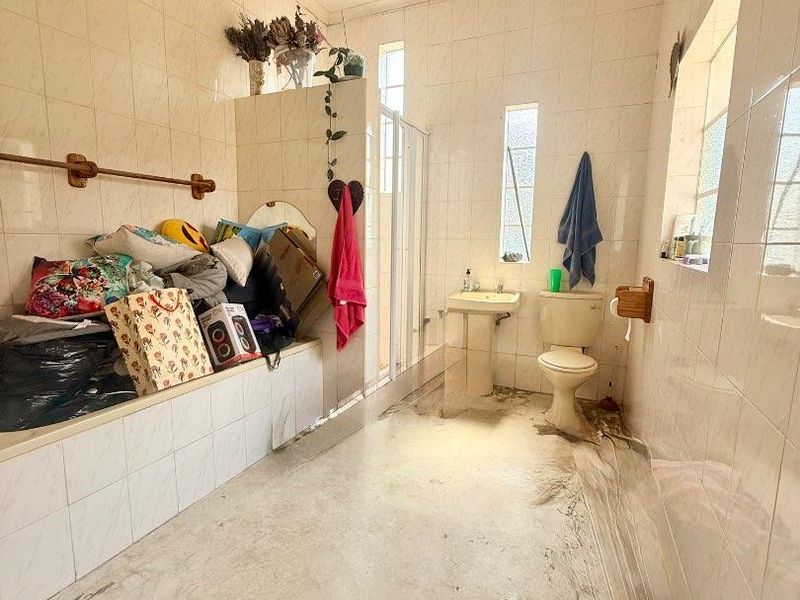 A dated bathroom featuring a built-in bathtub, pedestal sink, toilet, and shower enclosure with full-height wall tiling and a ceiling extractor fan.