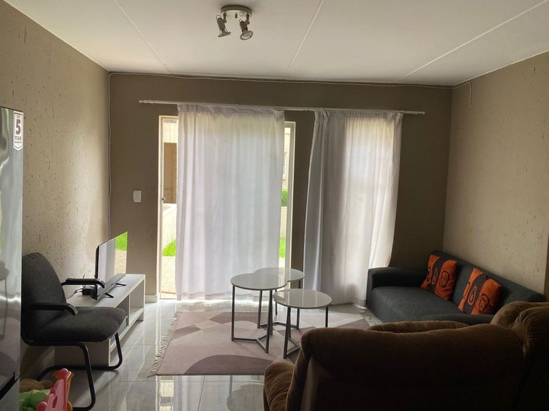 A living room area featuring tiled flooring and a sliding glass door providing access to the exterior.