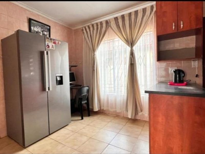 A dated kitchen area featuring tiled walls, built-in wooden cabinetry, and tiled flooring, offering potential for a modern renovation.