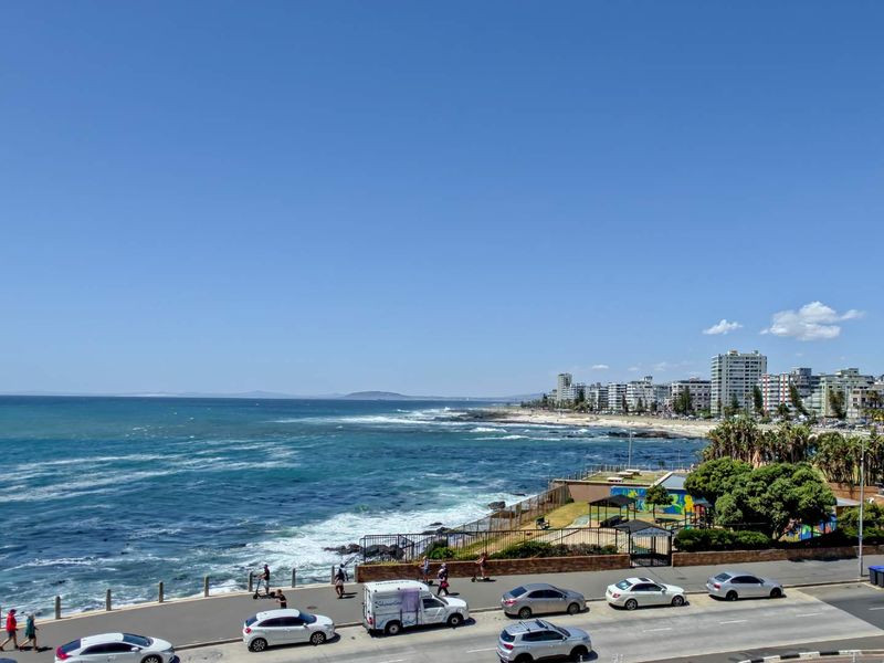 A scenic elevated view overlooking the coastline, ocean, and public promenade area.