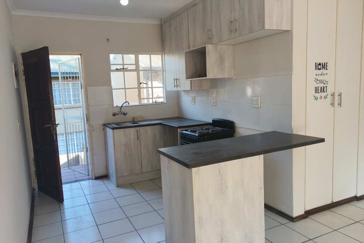 Functional kitchen featuring light wood-look cabinetry, dark countertops, tiled flooring, and a breakfast nook, providing a practical layout for daily meal preparation.