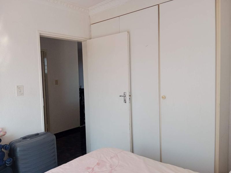 A bedroom featuring built-in cupboards with white finishes and decorative ceiling cornice, providing functional storage space.