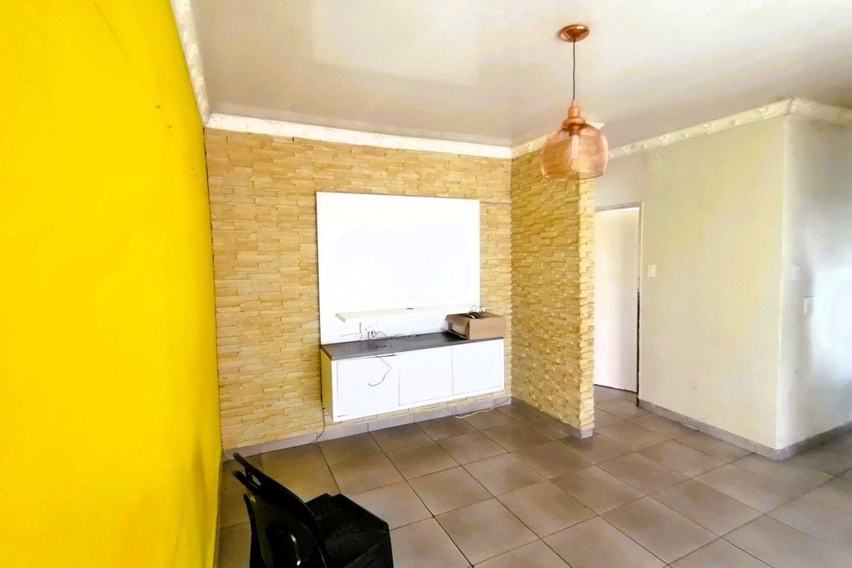 Living area featuring a stone-clad feature wall with a built-in media console, tiled flooring, and a decorative pendant light fixture.