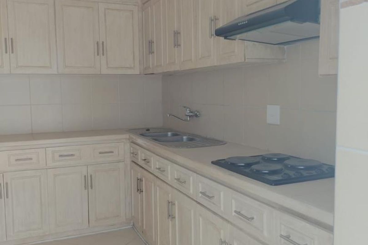 A functional kitchen featuring light-toned cabinetry, tiled flooring, a built-in hob, and an extractor fan.
