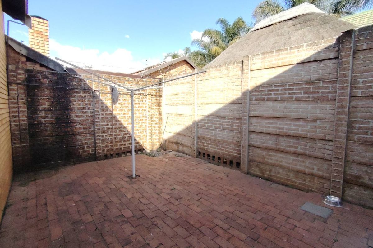 A private rear courtyard area featuring brick paving and high boundary walls, suitable for a utility or drying space.