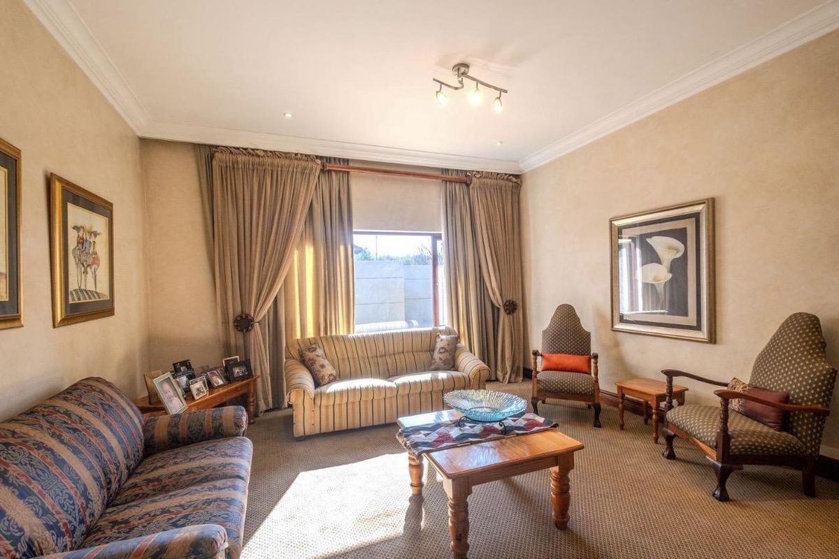 A comfortable living room featuring neutral wall finishes, carpeted flooring, and large windows with floor-to-ceiling curtains.