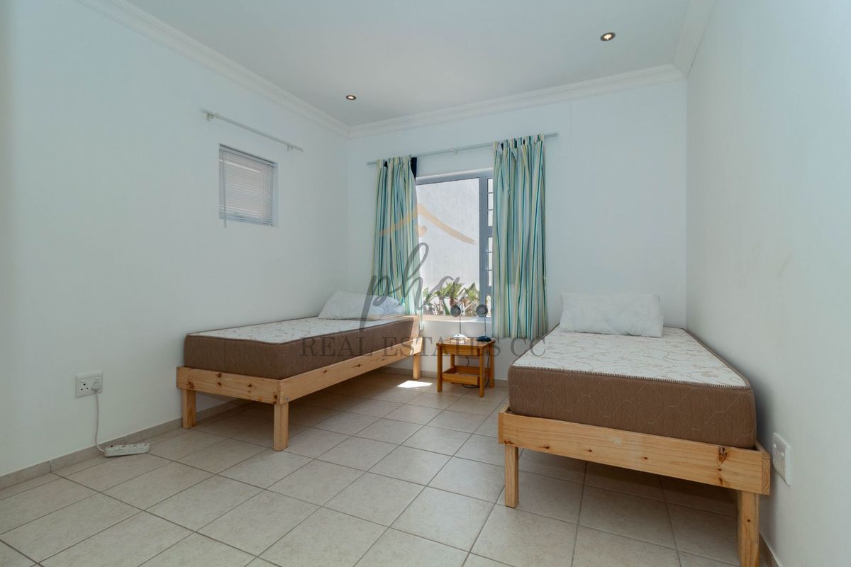 A functional bedroom featuring tiled flooring, recessed ceiling lighting, and a window with curtain tracks.