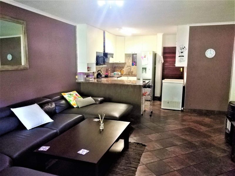 Open-plan living area featuring a kitchen with granite countertops and tiled flooring, seamlessly connected to the lounge space.