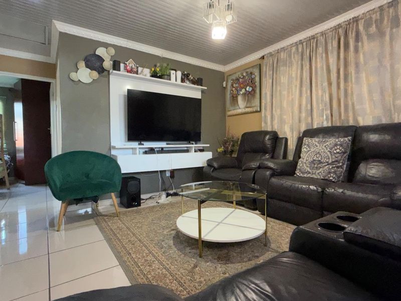 A comfortable living room featuring tiled flooring, a panelled ceiling with coved detailing, and a built-in media console unit.