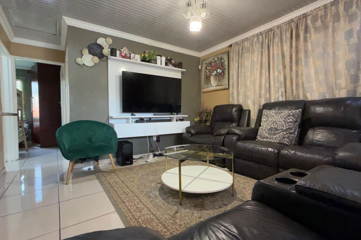 A comfortable living room featuring tiled flooring, a panelled ceiling with coved detailing, and a built-in media console unit.