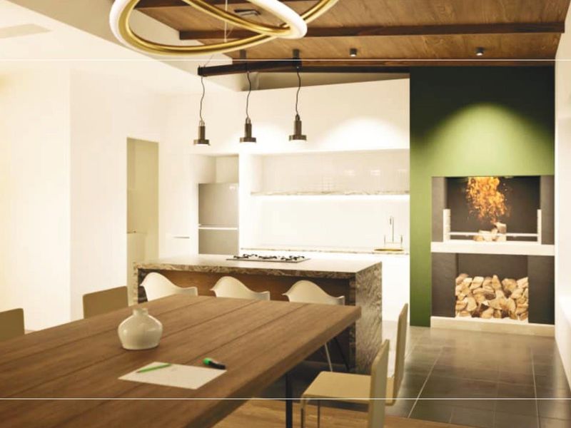 Modern open-plan living and kitchen area featuring a built-in fireplace, stone feature wall, timber ceiling beams, and a central kitchen island.