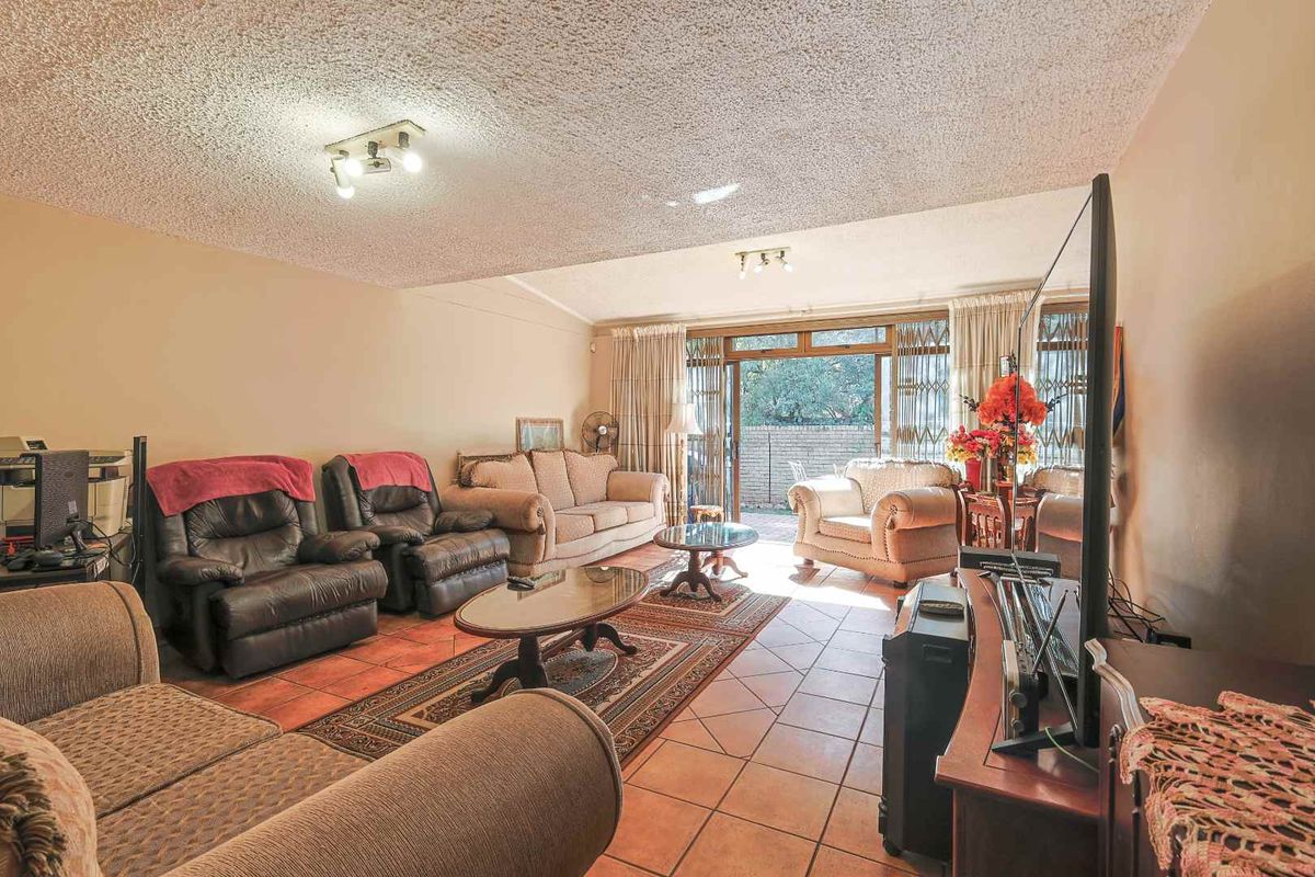 Spacious living room featuring terracotta floor tiles and sliding glass doors providing direct access to the outdoor patio area.