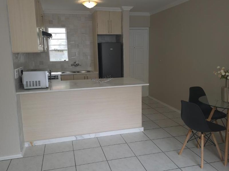 Open plan kitchen featuring light wood cabinetry, a breakfast bar island, and tiled flooring, seamlessly connecting to the dining area.
