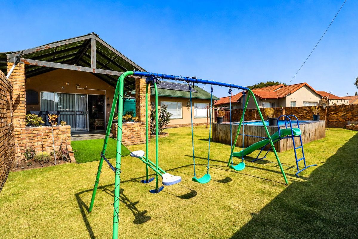Rear garden area featuring a covered patio, lawn, and an above-ground swimming pool with brick boundary walls.