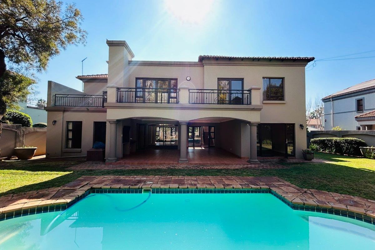 Rear view of the house featuring a swimming pool, a spacious covered patio, and an upper-level balcony with wrought iron railings.
