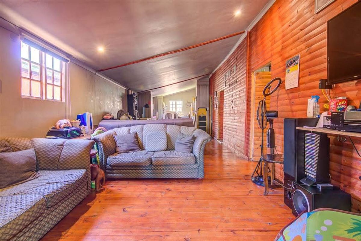 Spacious living area featuring timber wall cladding, polished timber flooring, and a sloped ceiling with recessed lighting in a cottage-style home.