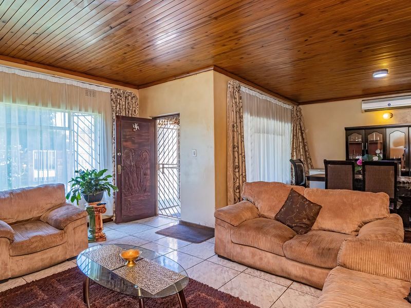 Spacious open-plan living and dining area featuring a warm timber-clad ceiling, tiled flooring, and a split-system air conditioner for climate control.