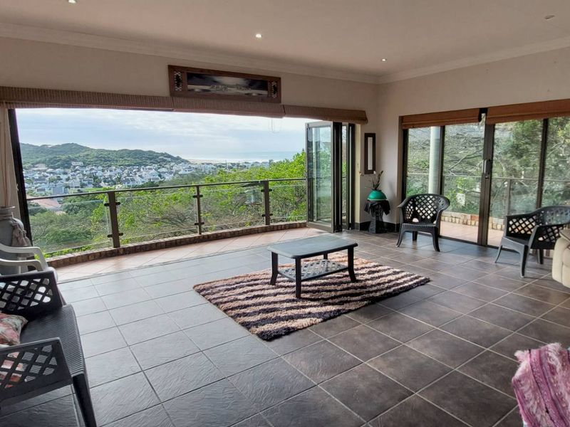 Spacious covered balcony featuring tiled flooring, glass balustrades, and bi-fold doors offering expansive elevated views of the surrounding landscape.