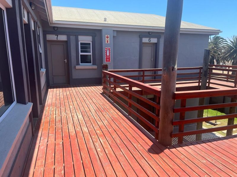 An elevated timber balcony deck providing access to apartment units, featuring wooden railings and external building access points.