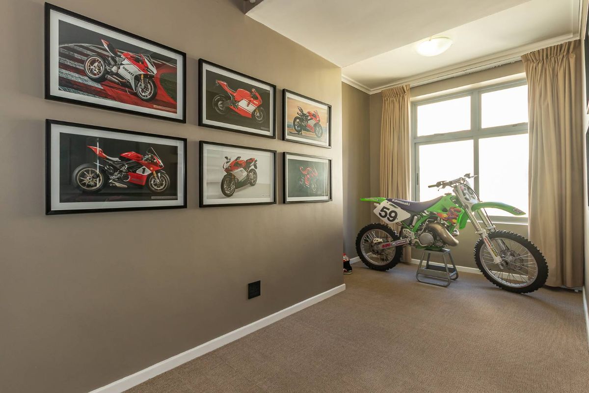 A well-maintained bedroom featuring neutral wall tones, carpeted flooring, and a large window with curtains, providing a clean and functional living space.
