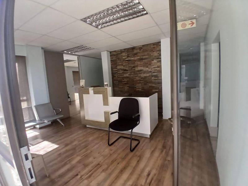 Professional office reception area featuring a built-in reception desk, wood-look flooring, and a decorative stone feature wall.