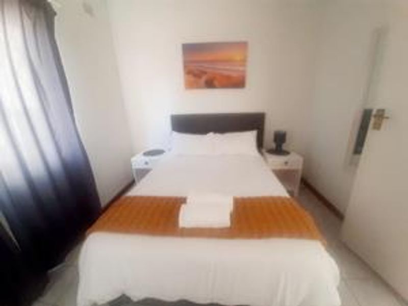 A compact bedroom featuring tiled flooring and a built-in cupboard, providing a functional sleeping space.