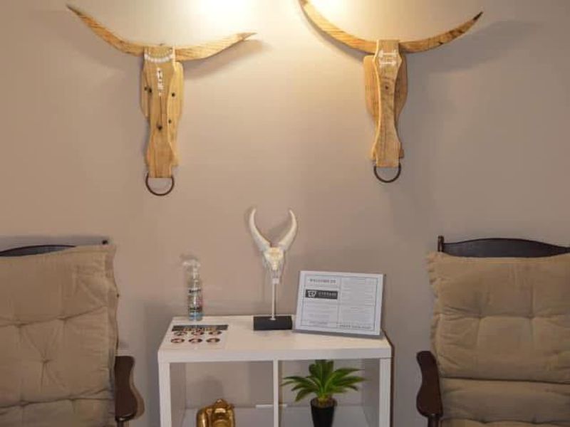 A cozy seating area featuring a wall-mounted light fixture and neutral wall tones, suitable for a relaxed lounge or waiting space.