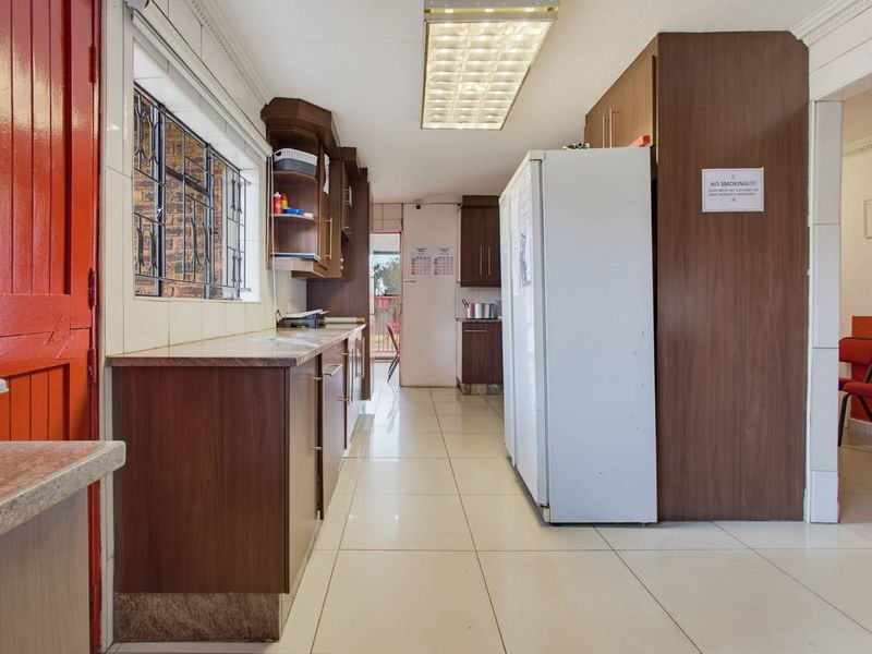 A functional kitchen featuring laminate cabinetry, granite countertops, and tiled flooring, providing a practical workspace with ample storage.