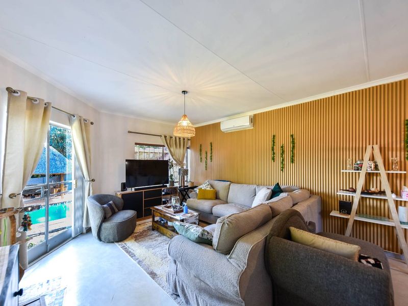 A bright living room featuring modern slatted wood wall paneling, a split-system air conditioner, and a sliding glass door providing access to the pool area.