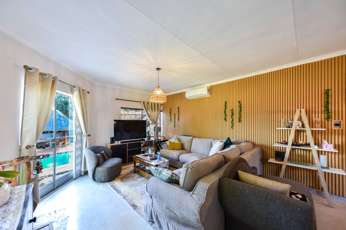 A bright living room featuring modern slatted wood wall paneling, a split-system air conditioner, and a sliding glass door providing access to the pool area.