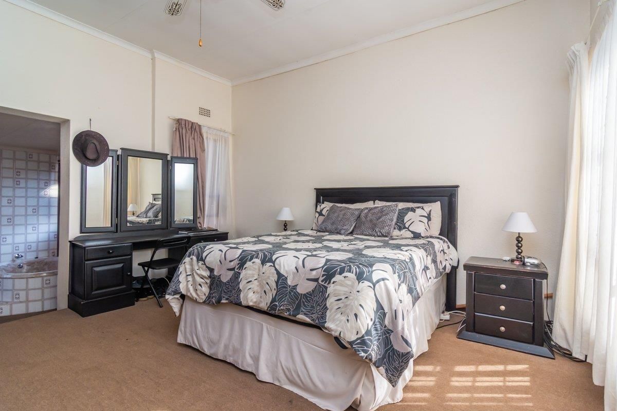 Spacious bedroom featuring neutral walls, carpeted flooring, and an adjoining en-suite bathroom area.