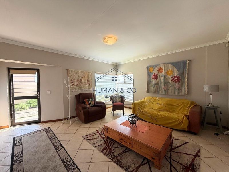 A spacious living room featuring neutral walls, ceramic tiled flooring, and decorative cornice detailing, providing a comfortable and functional living area.