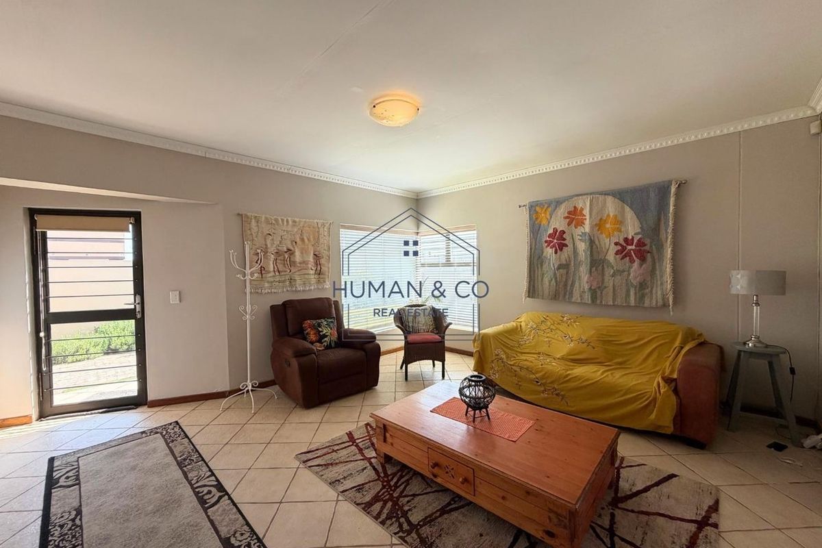 A spacious living room featuring neutral walls, ceramic tiled flooring, and decorative cornice detailing, providing a comfortable and functional living area.