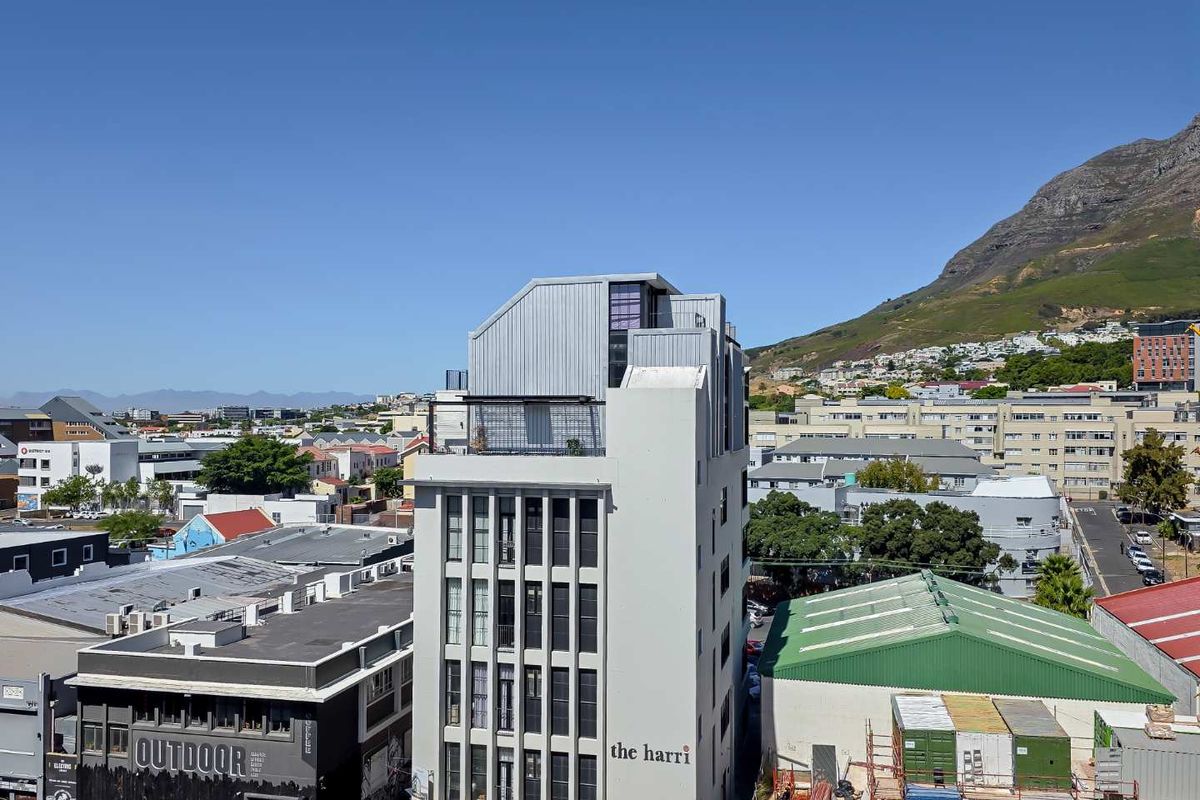 An aerial view of The Harri apartment building, showcasing its modern architectural design and urban surroundings with mountain views.