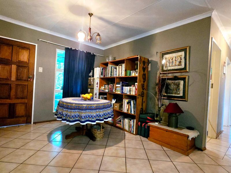 A living area featuring tiled flooring, a coved ceiling, and a solid timber entrance door, providing a functional and neutral space.