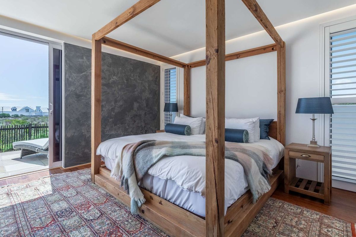 Spacious bedroom featuring hardwood flooring, a textured feature wall, and sliding glass doors opening onto a private balcony with outdoor views.