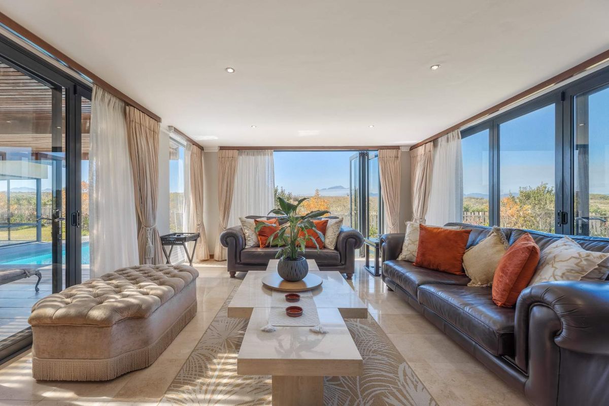 Spacious living room featuring large floor-to-ceiling glass sliding doors that provide seamless indoor-outdoor flow and expansive views of the surrounding landscape.