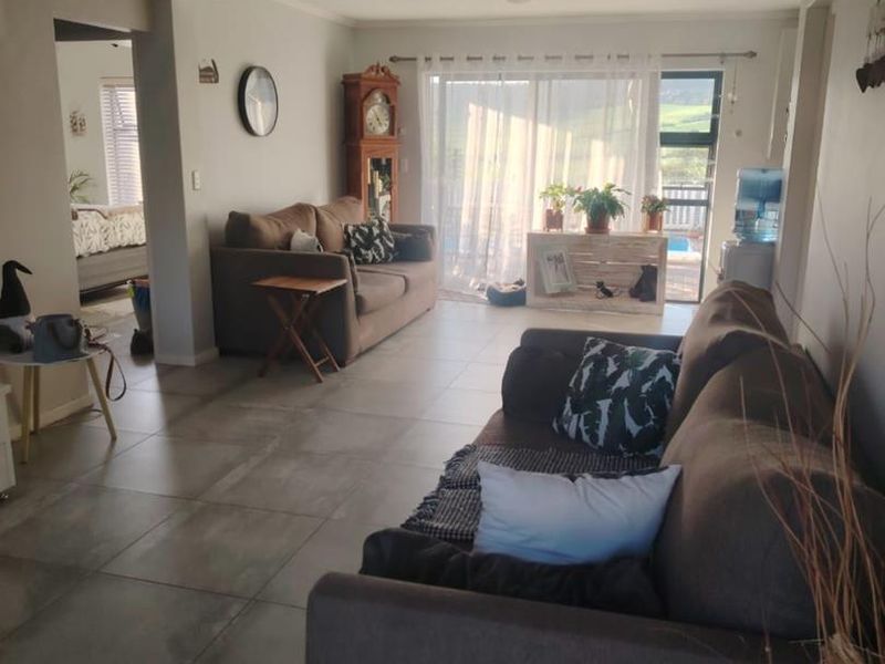 Spacious open-plan living area featuring large format floor tiles, exposed beam ceilings, and a sliding glass door providing natural light and outdoor access.